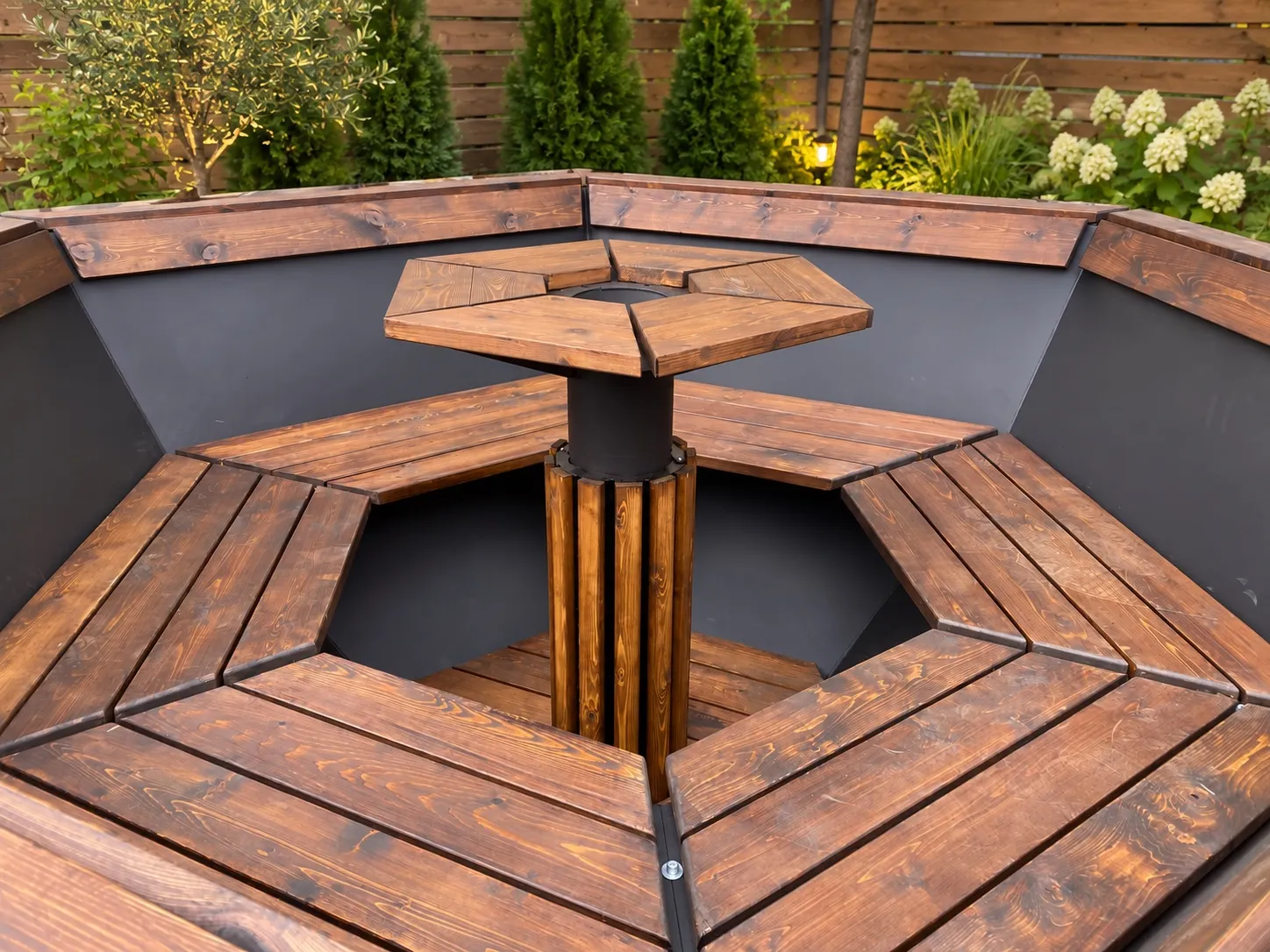 The inside of a Siberia Large seen from above: a cedar bench ring around the steel wall and a hexagonal cedar centre table on a steel post.