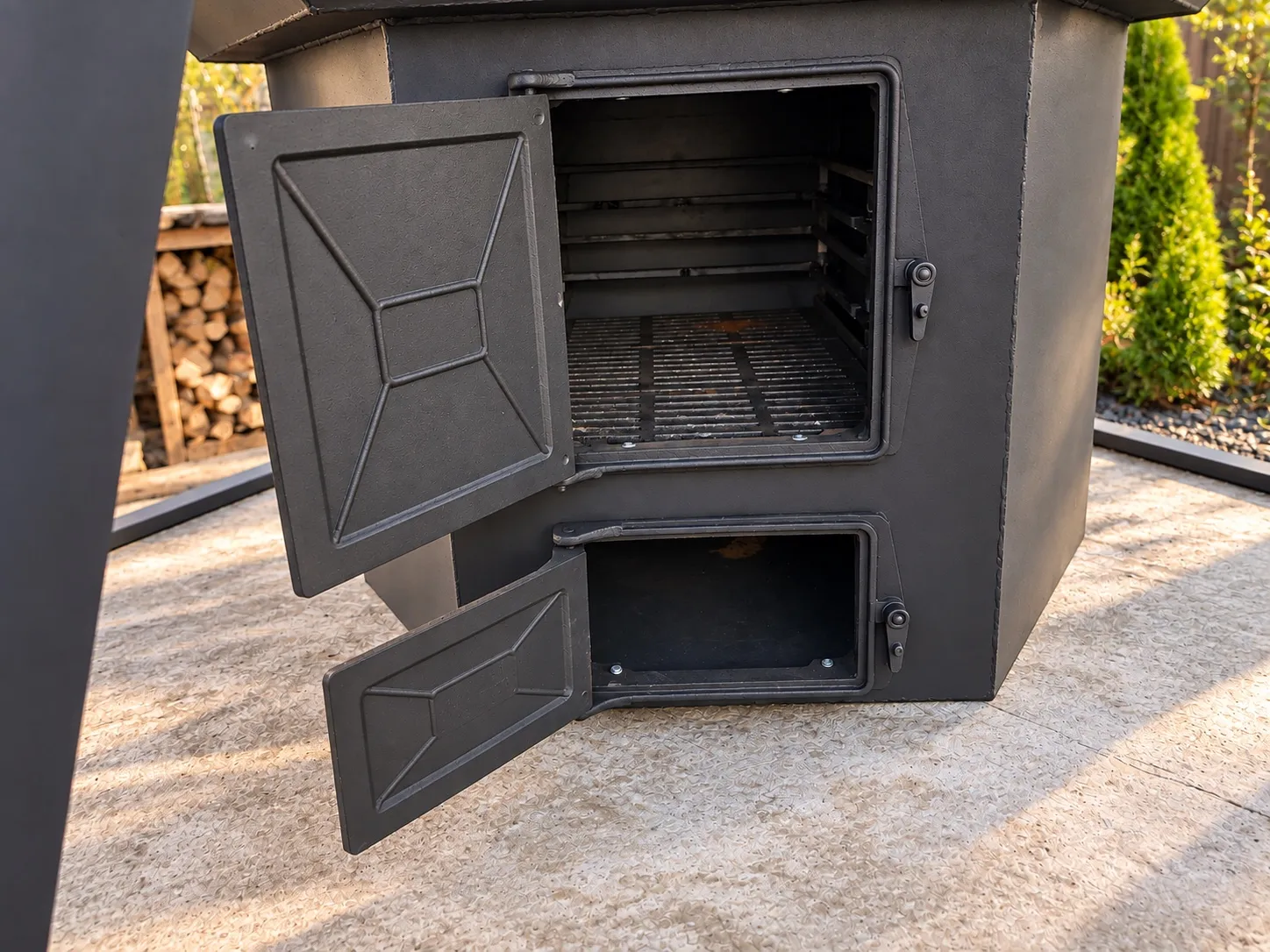 An open firebox on a Siberia Large, showing the fire grate and a separate ash drawer below it, both with hinged doors.