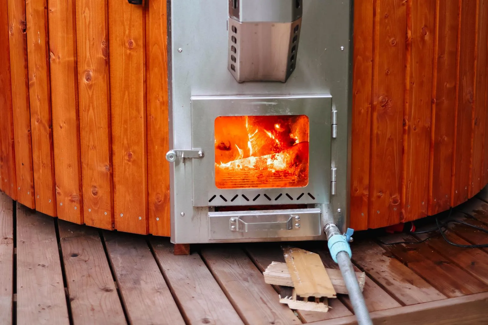 The fire lit behind the glass door of a stove built into the side of a tub, with the chimney above it.
